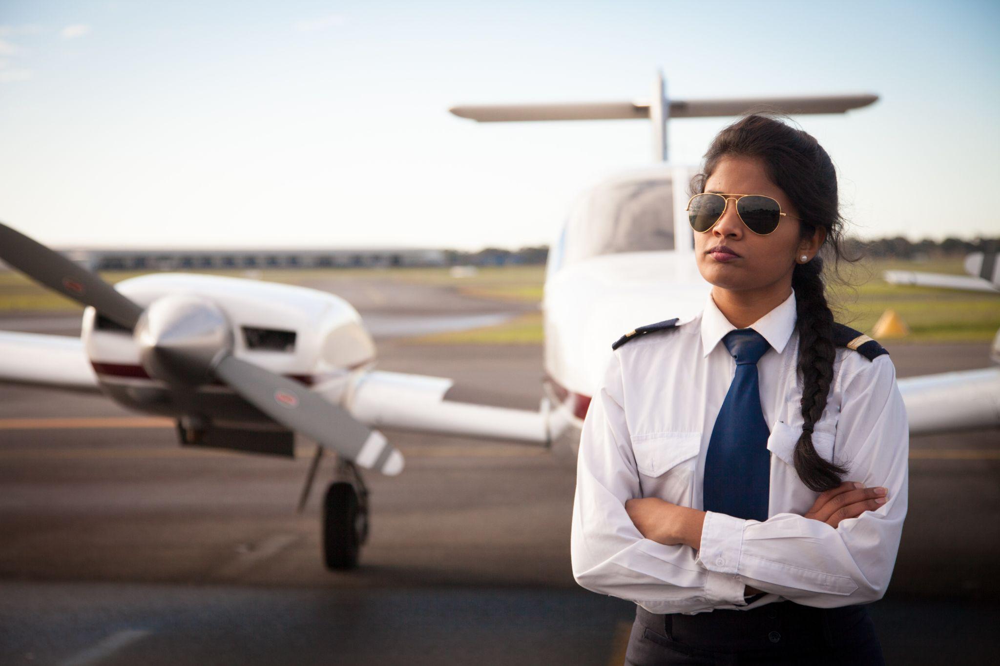 Female pilot standing in front of her plane.
