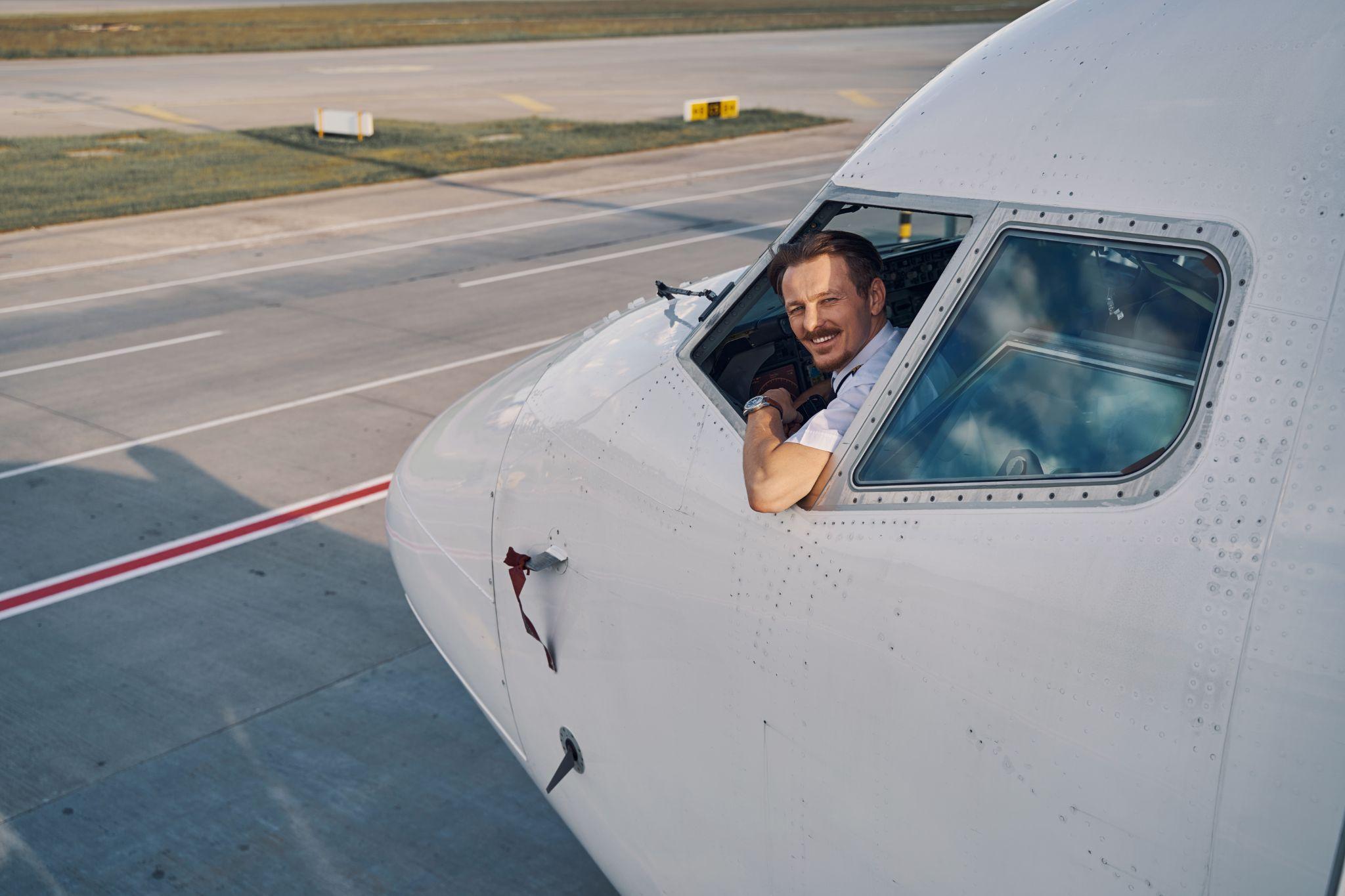 Joyous aviator posing for the camera from the flight deck.